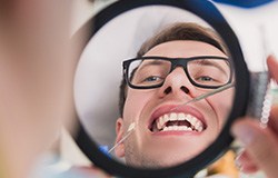 Dental implant patient looking at new tooth in mirror