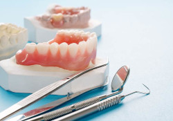 Full and partial dentures lying on table with dental tools