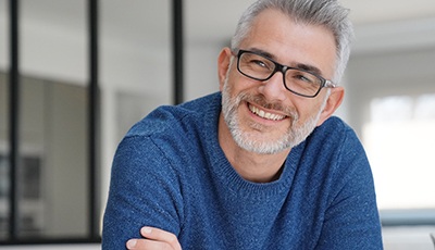 Man with glasses smiling with arms folded